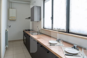 A modern kitchen with a gas stove, sink, and a window with curtains. - Homiday - Maximum's Landing (Roseto degli Abruzzi)