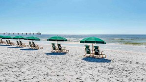 A beach with rows of green umbrellas and wooden beach chairs. - 5th Floor Gulf-Front Condo w Free WiFi, Shared Hot Tub, Outdoor Pool, & More (Fort Walton Beach)
