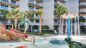 A hotel pool area with a water slide, a frog statue, and palm trees. - 5th Floor Gulf-Front Condo w Free WiFi, Shared Hot Tub, Outdoor Pool, & More (Fort Walton Beach)