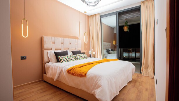Ein modernes Schlafzimmer mit einem großen Bett, einer Kandelaber und einer Schiebetür zu einem Balkon.