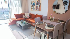 Ein modernes Wohnzimmer mit Sofa, Couchtisch und Esstisch, gedeckt für eine Mahlzeit.