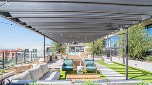 Una terraza en la azotea con mobiliario exterior, piscina y vistas a la ciudad.