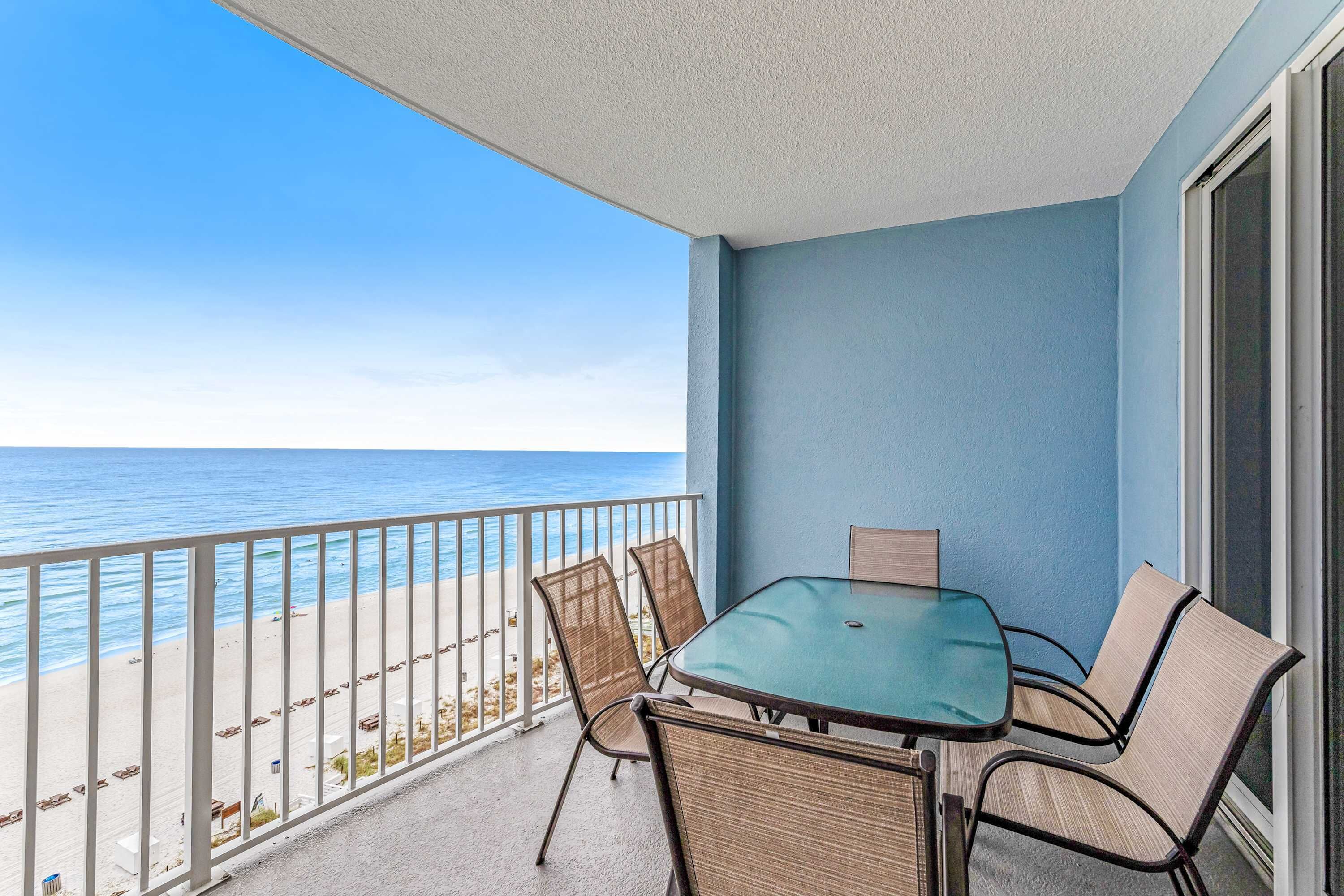 Ein Balkon mit Glastisch und Stühlen, mit Blick auf einen Strand.