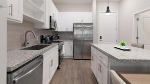 A modern kitchen with white cabinetry, stainless steel appliances, and a granite countertop. - Landing | Amazing 1BD, Yoga Studio, Gym (Four Corners)