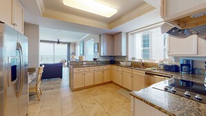 A spacious kitchen with granite countertops, stainless steel appliances, and light wood cabinets. - Gorgeous, cozy beachfront condo with pool, pool spa & beach access (Perdido Key)