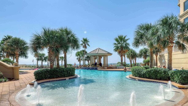 A pool area with palm trees, a gazebo, and a clear blue sky. - Gorgeous, cozy beachfront condo with pool, pool spa & beach access (Perdido Key)