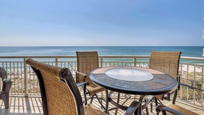 A round table with wicker chairs on a balcony overlooking the beach. - Gorgeous, cozy beachfront condo with pool, pool spa & beach access (Perdido Key)