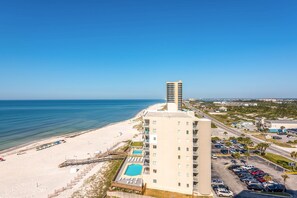 Ein Hochhaus-Hotel mit Pool im Erdgeschoss, direkt neben einem Strand.