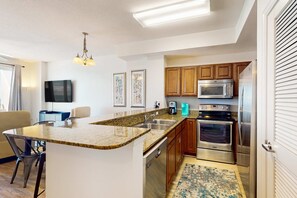A modern kitchen with granite countertops, stainless steel appliances, and wooden cabinets. - Newly Updated, 9th Floor Gulf-front Condo. Beach Chair Service Included (Panama City Beach)