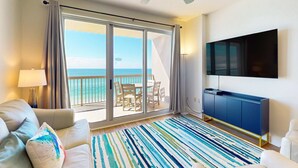 Ein modernes Hotelzimmer mit Balkon, einem Flachbildfernseher, einer Couch und einem Streifenmuster-Teppich.