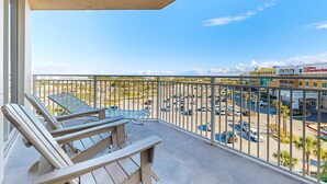 Ein Balkon mit zwei Adirondack-Stühlen und einem Tisch, mit Blick auf einen Parkplatz und ein Gebäude mit einem Schild für ein Gartenrestaurant.