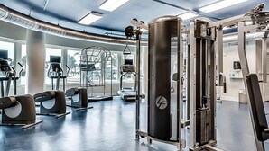 Ein Fitnessstudio mit verschiedenen Trainingsgeräten, darunter ein Squat-Rack und Laufbänder.