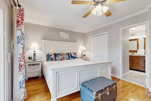 A bedroom with a large bed, two bedside tables with lamps, a ceiling fan, and a suitcase on the floor. - Striking condo near the beach, with on-site pool & washer/dryer (Miramar Beach)