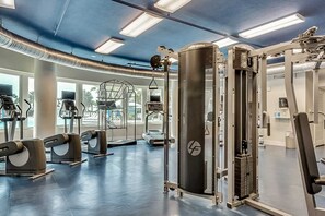 A modern gym with various exercise equipment, large windows, and a blue ceiling. - 2nd Floor Welcoming Condo At Waterscape Children's Playground, 2 Hot Tubs (Fort Walton Beach)