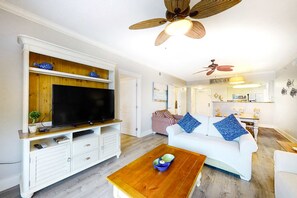 A living room with a flat-screen TV, white sofa, and a wooden coffee table. - 2nd Floor Welcoming Condo At Waterscape Children's Playground, 2 Hot Tubs (Fort Walton Beach)