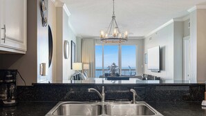 A modern kitchen with a double sink, a coffee maker, and a view of the balcony. - 25th-floor, waterfront condo with picturesque views, pools & fitness room (Panama City Beach)