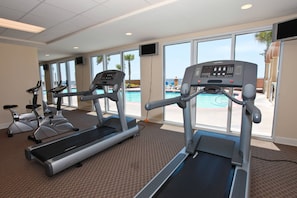 A gym with treadmills and stationary bikes, large windows with a pool view. - Beach-chic, 7th-floor condo with incredible Gulf-front views, gym, hot tub & 2 pools (Panama City Beach)
