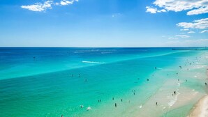 A beach with clear turquoise water, a pier, and people enjoying the shore. - Beach-chic, 7th-floor condo with incredible Gulf-front views, gym, hot tub & 2 pools (Panama City Beach)