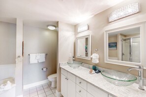 Een moderne badkamer met een glazen wastafel, een grote spiegel en een toilet.