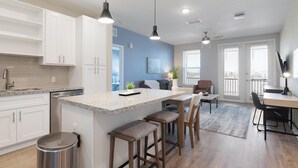 A modern kitchen with white cabinets, a granite countertop, and a stainless steel trash can. - Landing | Beautiful 2BD, Yoga Studio, Gym (Four Corners)