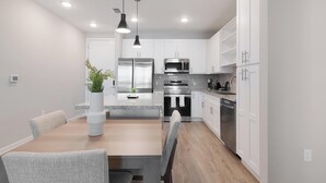 A modern kitchen with white cabinets, stainless steel appliances, and a central island. - Landing | Beautiful 2BD, Yoga Studio, Gym (Four Corners)