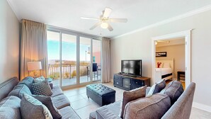 Ein modernes Wohnzimmer mit einer Sofagarnitur, einem Fernseher und einem Deckenventilator.