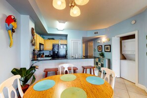 Una cocina moderna con armarios de madera, un refrigerador y un comedor con mesa y sillas de madera.