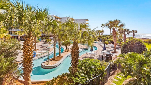 Un resort con piscina, palmeras y vista al océano.