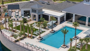 Ein modernes Resort mit großem Pool, Liegestühlen und einem gepflegten Garten.