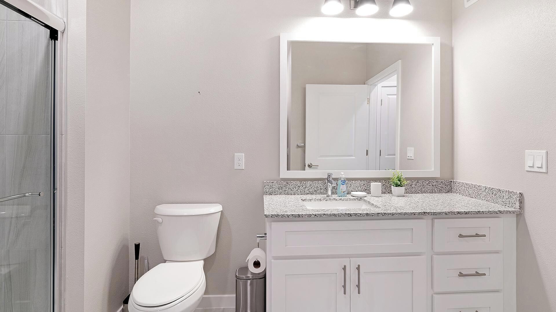 Une salle de bain équipée de toilettes, d’un lavabo, d’un miroir et de placards.