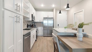Eine moderne Küche mit weißen Schränken, Edelstahlgeräten und einer Holz Arbeitsplatte.