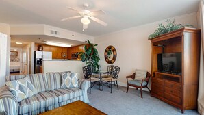 A living room with a sofa, coffee table, dining table, chairs, and a TV cabinet. - 6th Floor Welcoming Condo At Waterscape Children's Playground, 2 Hot Tubs (Fort Walton Beach)