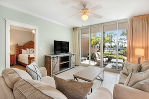 A hotel room with a balcony, a television, a sofa, and a dining table. - Ground-Floor Condo At Waterscape Beach Service Included Seasonally, Playground (Fort Walton Beach)