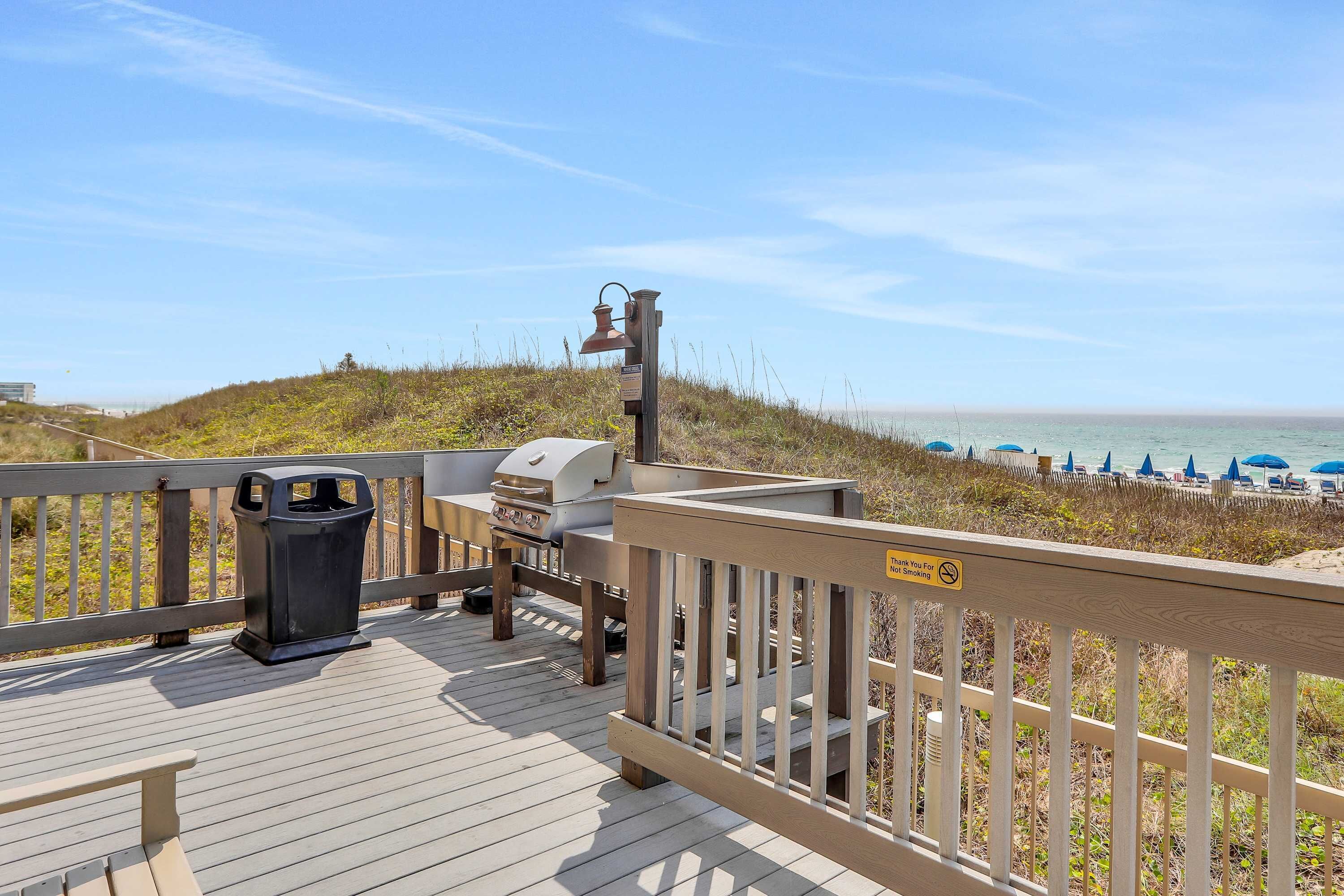 A wooden deck with a grill, trash can, and a sign indicating no smoking.