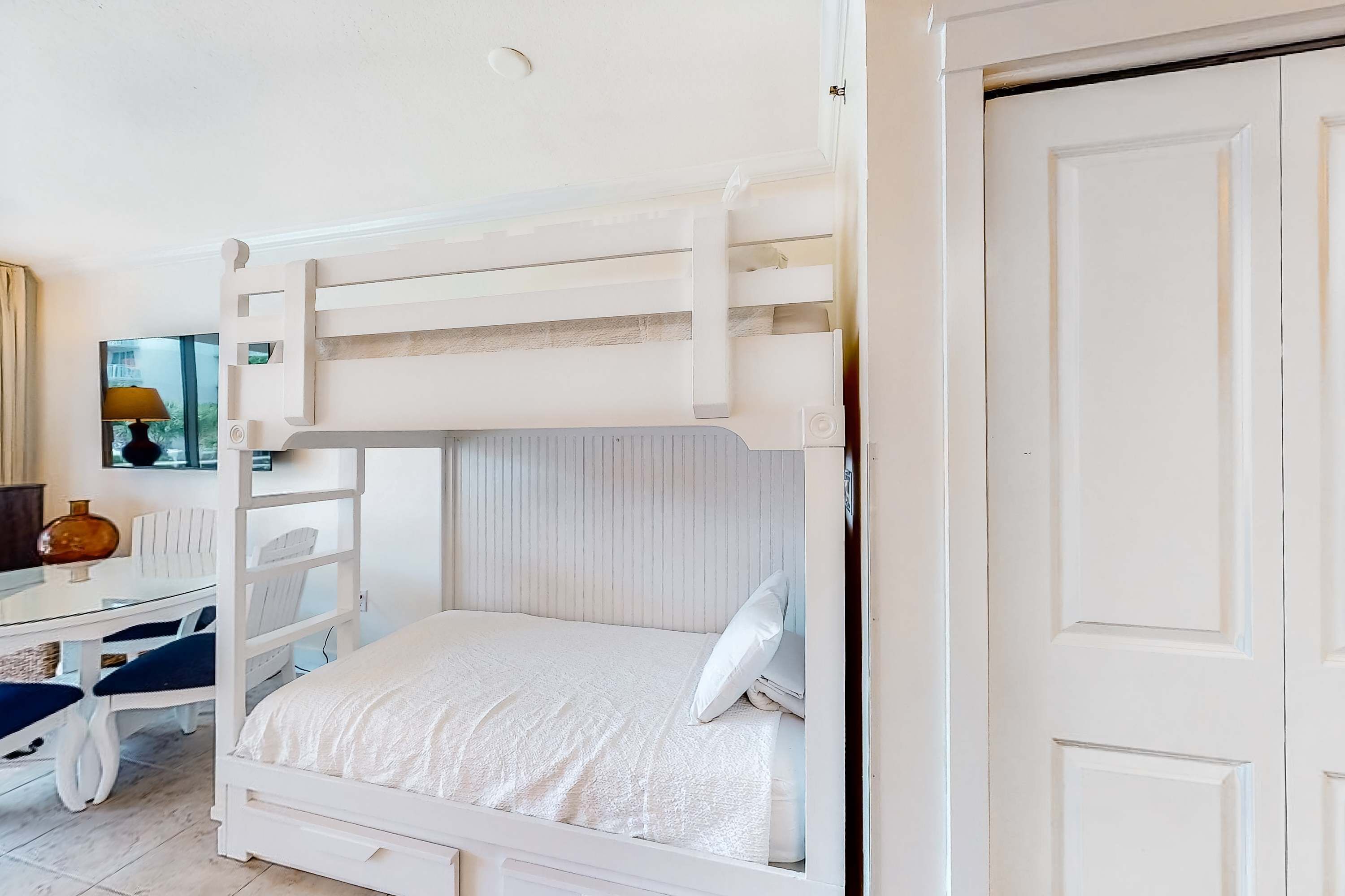 Una cama individual sobre otra con escritorio y silla, una lámpara y una ventana con vistas.