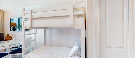 Una cama individual sobre otra con escritorio y silla, una lámpara y una ventana con vistas.