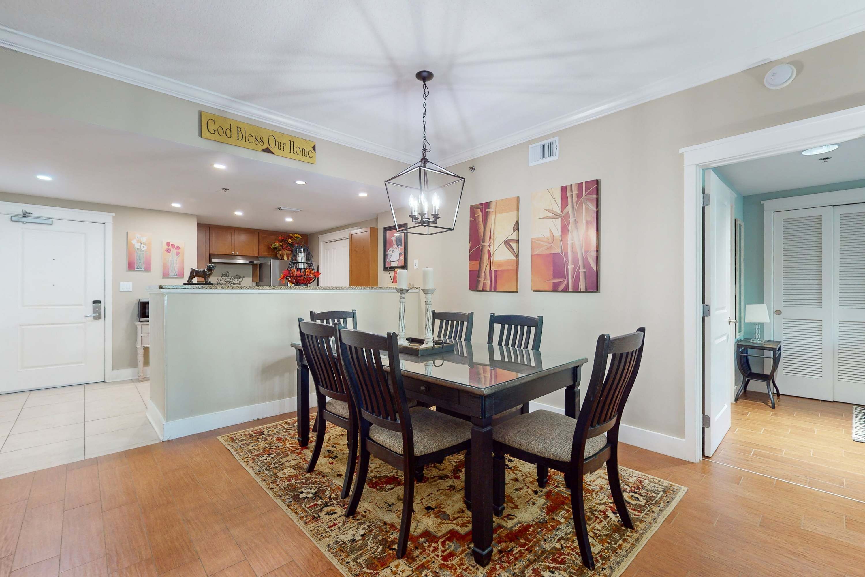 A dining area with a glass-top table, dark wooden chairs, and a patterned rug.