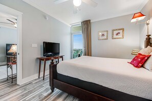 A hotel room with a large bed, a television, a desk with a lamp, and a window with curtains. - Cozy, Tropical Condo On Okaloosa Island, Children's Playground, 2 Hot Tubs (Fort Walton Beach)
