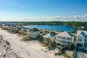 Un quartier résidentiel situé sur la côte, avec des propriétés en bord de mer, notamment des maisons dotées de balcons et de terrasses, ainsi qu’une plage de sable.