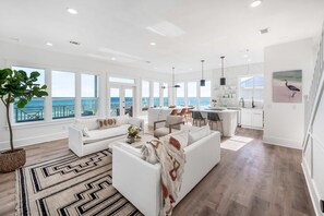 Un salon spacieux avec un canapé blanc, une table basse et une vue sur l’océan.