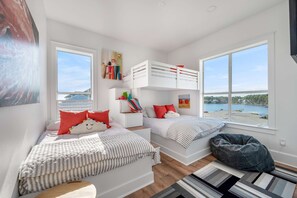Une chambre conçue pour les enfants, avec des lits superposés, un fauteuil poire et une vue sur un lac.