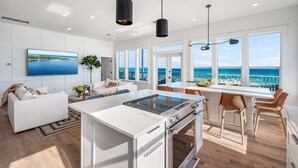 Una cucina moderna con un'isola grande, mobili bianchi e vista sull'oceano.