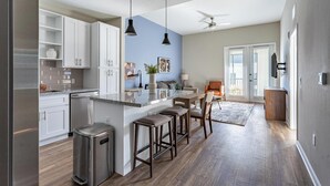 Una cocina moderna con armarios blancos, encimera de granito y una isla central con taburetes de bar.