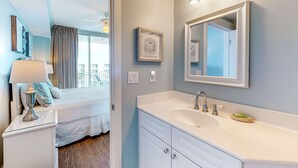 A modern bathroom with a large mirror, white vanity, and a view of the balcony. - Elegant, Decorated Condo At Waterscape Waterfall, Lazy River (Fort Walton Beach)