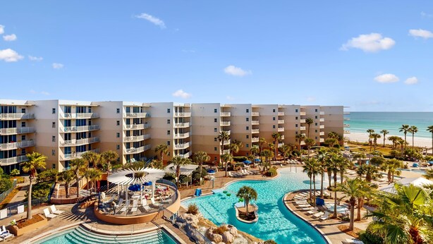 Ein Resort mit mehrstöckigen Gebäuden, einem zentral gelegenen Pool und Blick auf den Strand.
