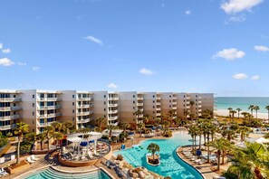 Et resort med flereetagers bygninger, en central swimmingpool og havudsigt.