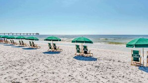 Ein Strand mit Reihen grüner Sonnenschirme und Holzliegen.