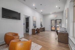 A modern interior with a reception desk, wooden flooring, and a view through a glass door. - Landing | Modern 1BD, Gym, Clubhouse (Asheville)