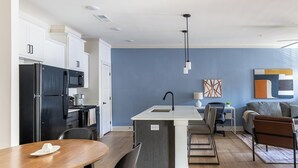 Una cocina moderna con armarios blancos, un refrigerador negro y una isla central con un lavamanos.