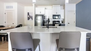 Una cocina moderna con armarios blancos, un refrigerador de acero inoxidable, un microondas y una isla grande con pileta.